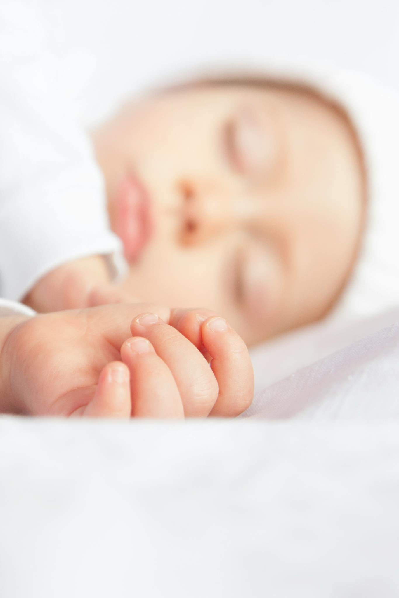A serene and innocent close-up of a sleeping newborn baby with soft focus.