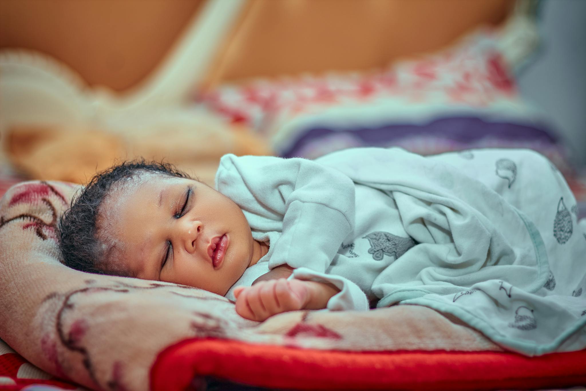 A serene image of a sleeping baby wrapped in a soft blanket indoors.