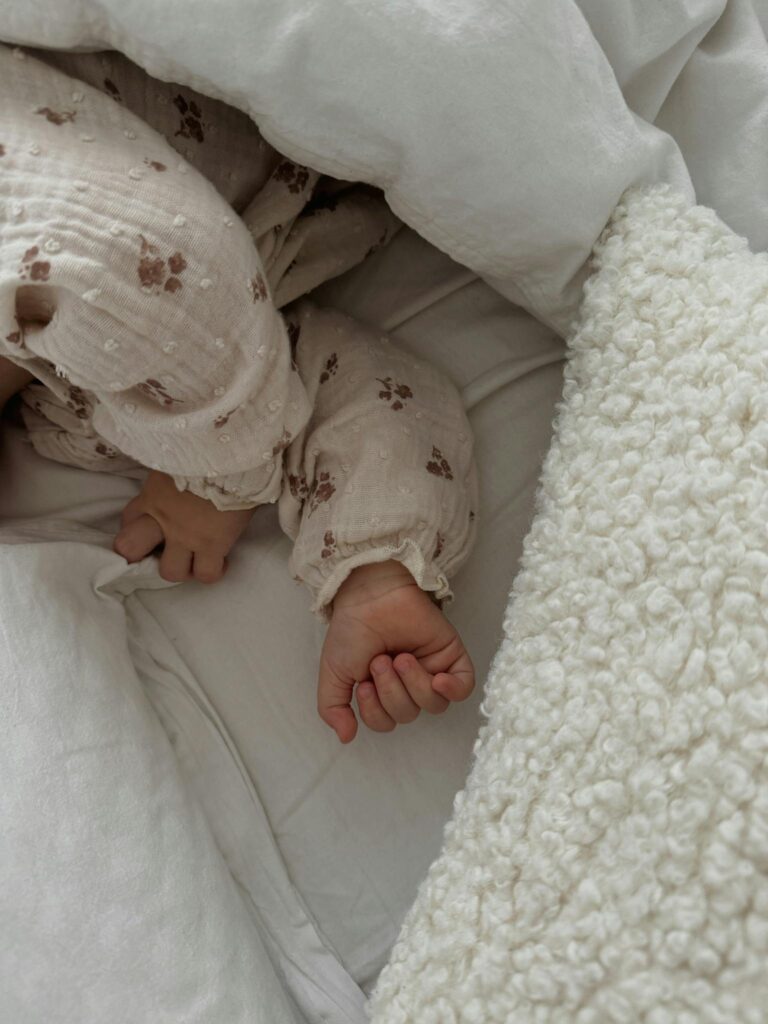 Adorable sleeping baby in soft bedding, showcasing peaceful rest and comfort.